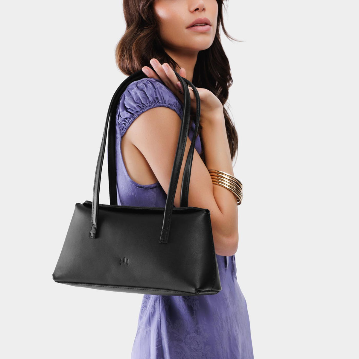 Black | Woman wearing a black leather bowler bag against a white background