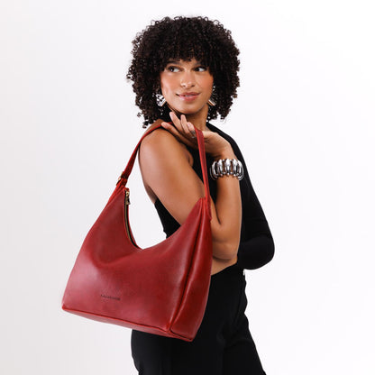 Chili Red*Large | Model holding u-shaped, flat-bottomed leather shoulder bag with adjustable strap