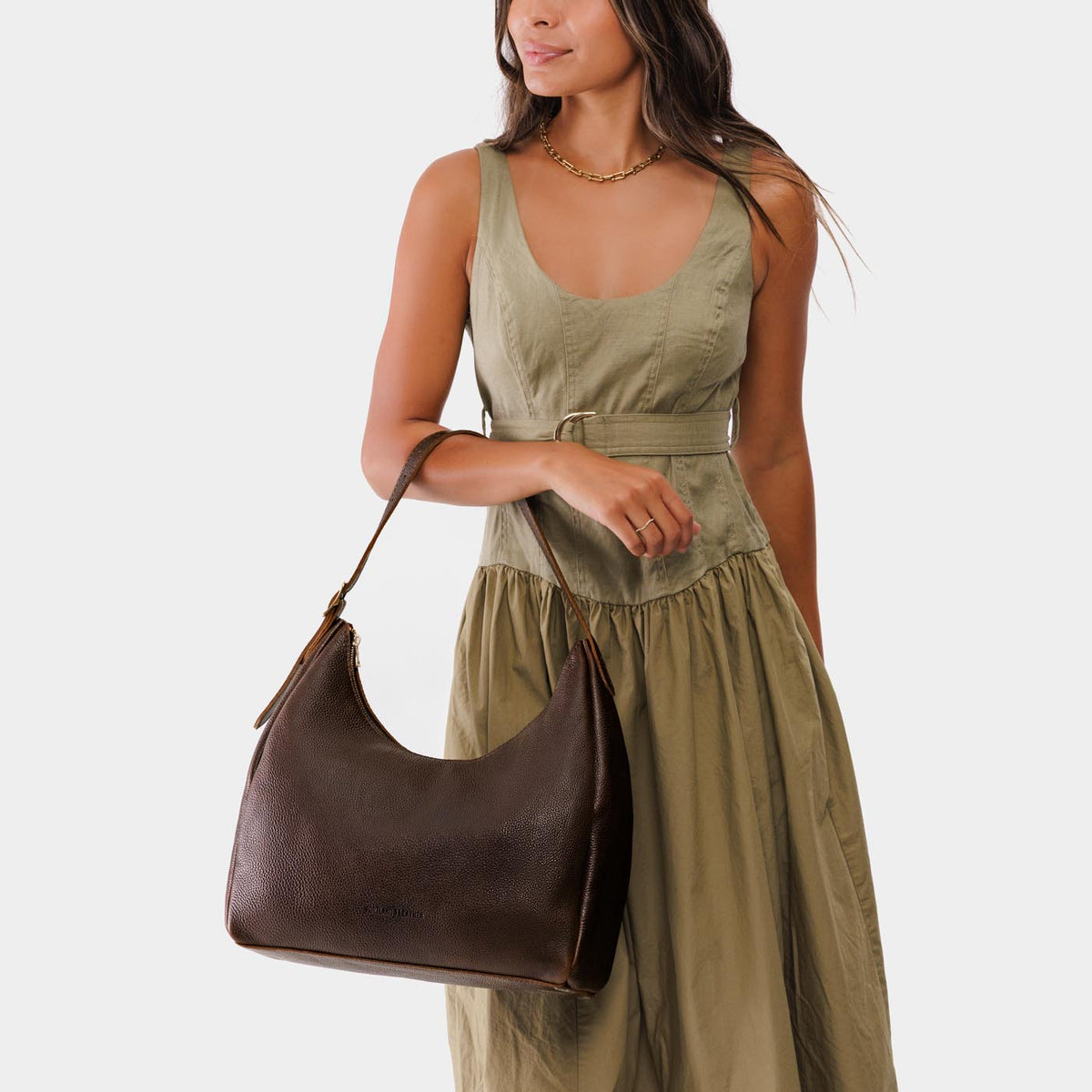 Coldbrew*Large | Model holding u-shaped, flat-bottomed leather shoulder bag with adjustable strap