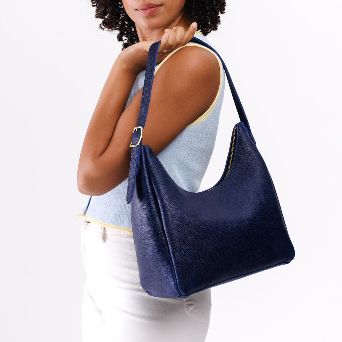 Cobalt*Medium | Model holding u-shaped, flat-bottomed leather shoulder bag with adjustable strap