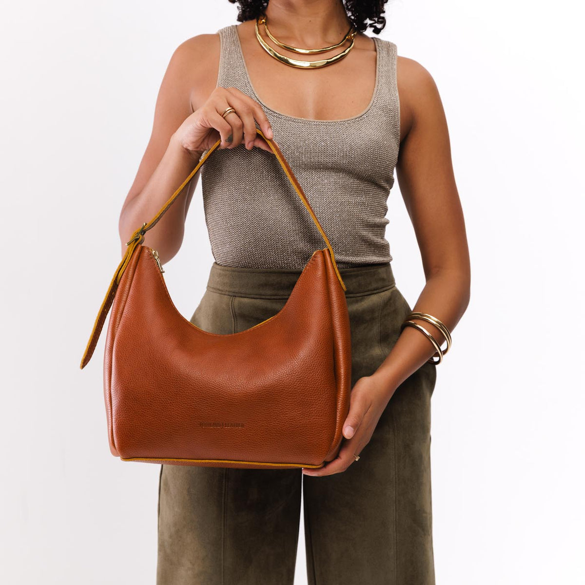 Sienna*Medium | Model holding u-shaped, flat-bottomed leather shoulder bag with adjustable strap