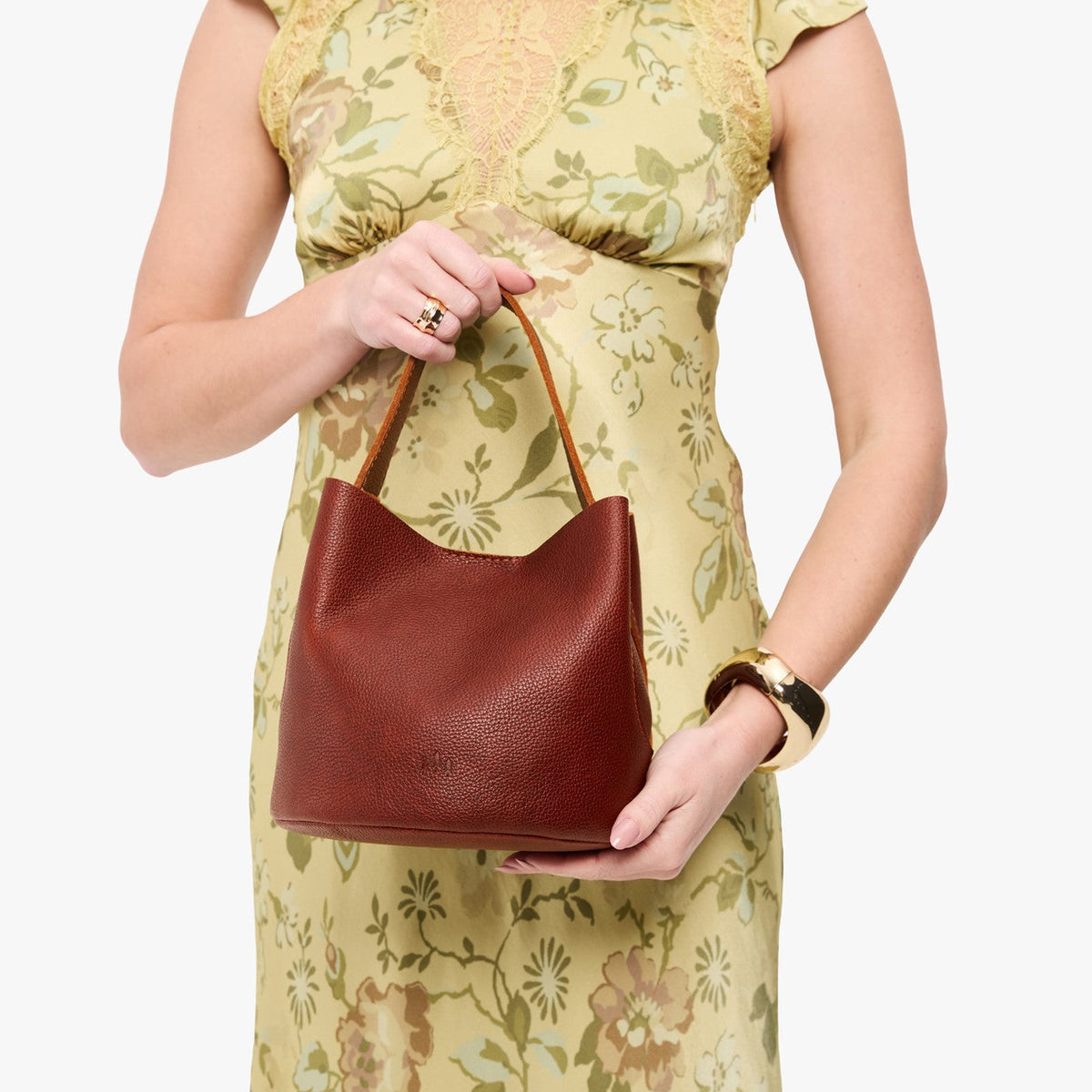 Nutmeg*Small | Model holding symmetrical bucket bag with handle, latch closure, and removable crossbody strap