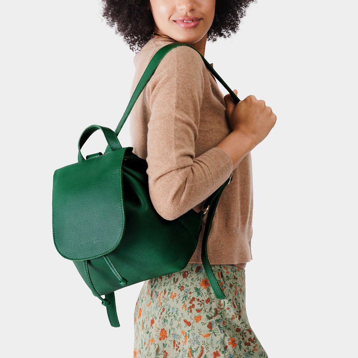 Bacalar | Pebbled green leather drawstring backpack being worn by a person wearing a brown sweater.