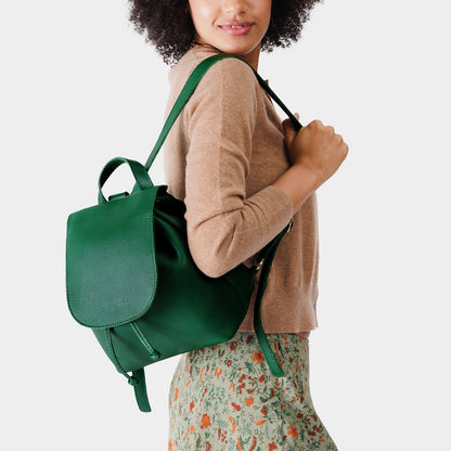 Bacalar | Pebbled green leather drawstring backpack being worn by a person wearing a brown sweater.