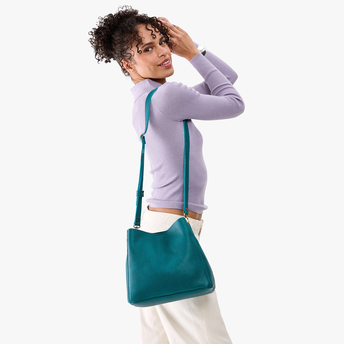 Aquarius | Model wearing symmetrical bucket bag with latch closure and removable crossbody strap