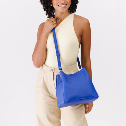 Astro Blue | Model wearing symmetrical bucket bag with latch closure and removable crossbody strap