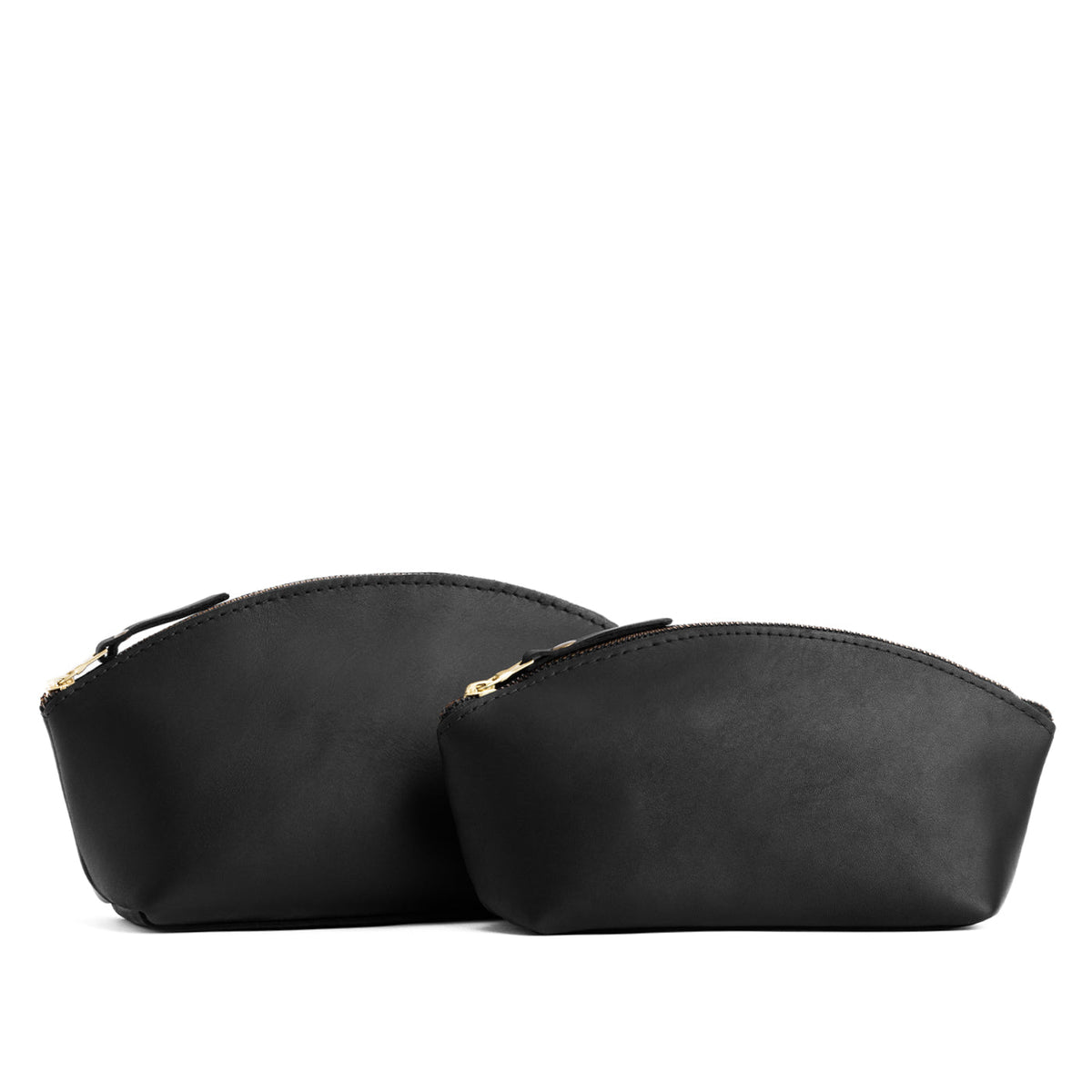 Black | Size comparison shot of two spacious leather makeup bags with curved seams and top zipper