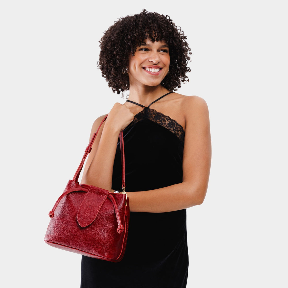 Chili Red*Small | Model holding symmetrical leather bag with leather drawstring closure and adjustable shoulder strap