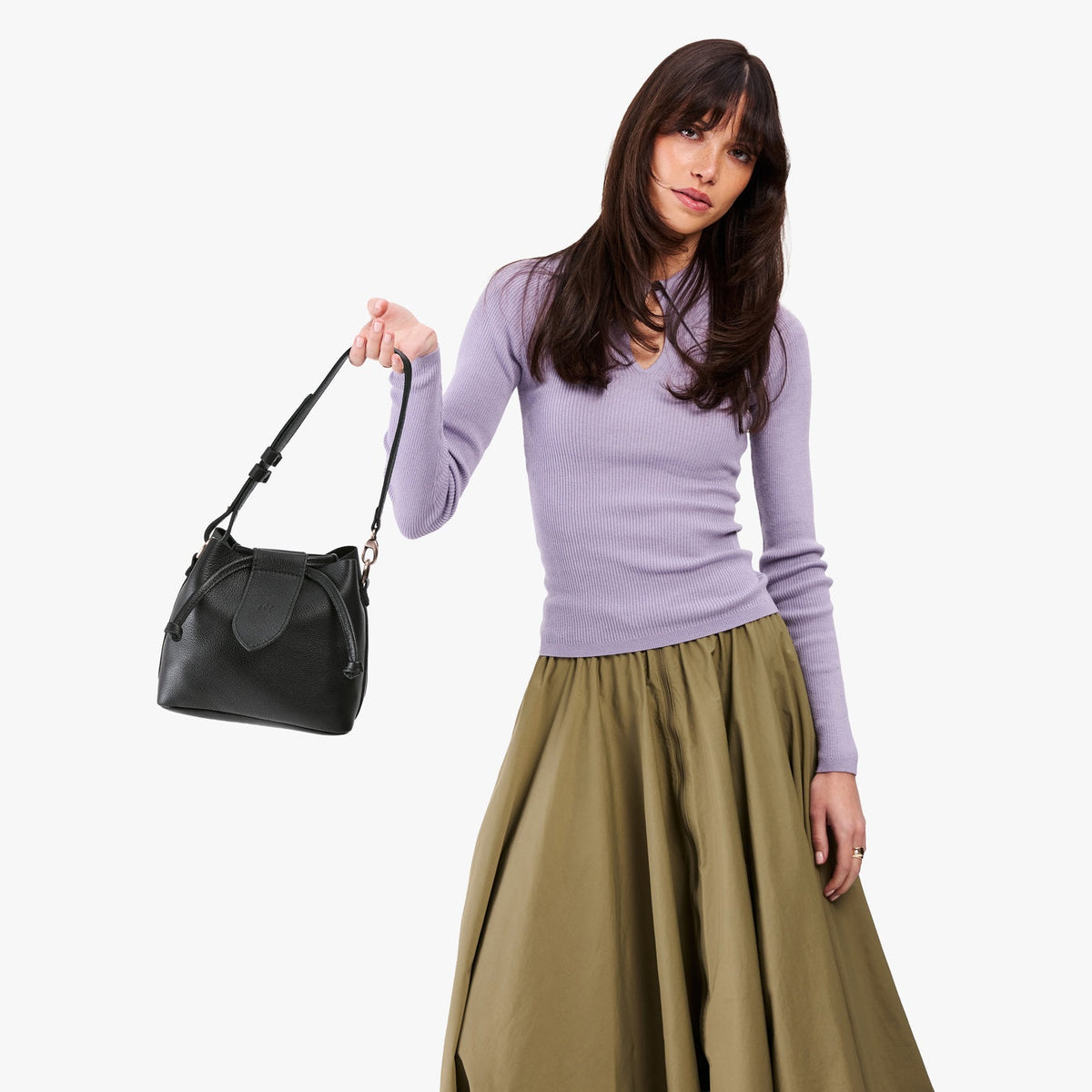 Pebbled--black*Small | Model holding symmetrical leather bag with leather drawstring closure and adjustable shoulder strap