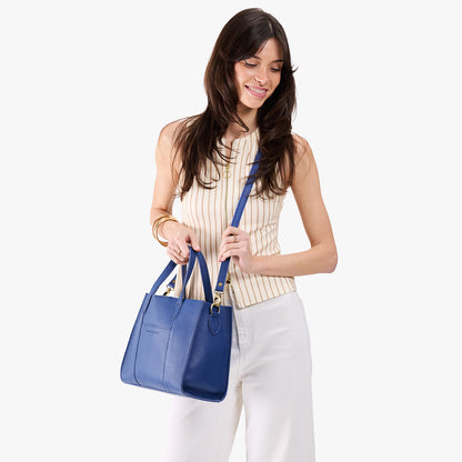 Molino Blue | Model holding structured mid-size tote bag with overlapping panels and crossbody strap