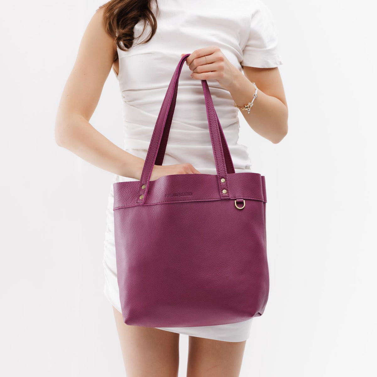 Iris*Medium*Classic | Model holding leather tote bag with riveted straps and exterior key loop