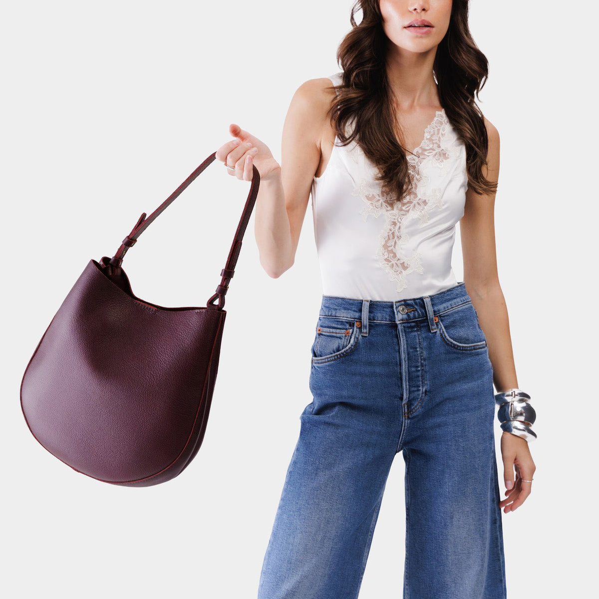 Plum*Large | Woman wearing rounded shoulder bag with adjustable strap on a white background
