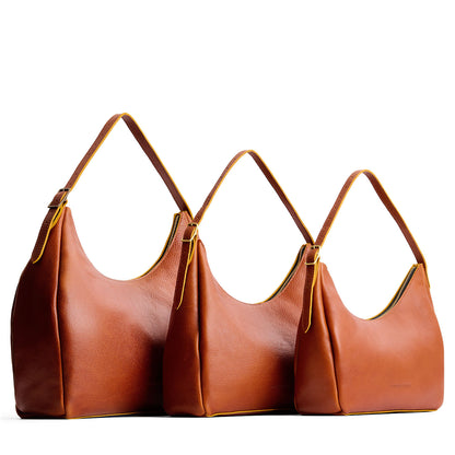 Sienna | Size comparison image of oversized, large, and medium u-shaped, flat-bottomed leather shoulder bags with adjustable strap