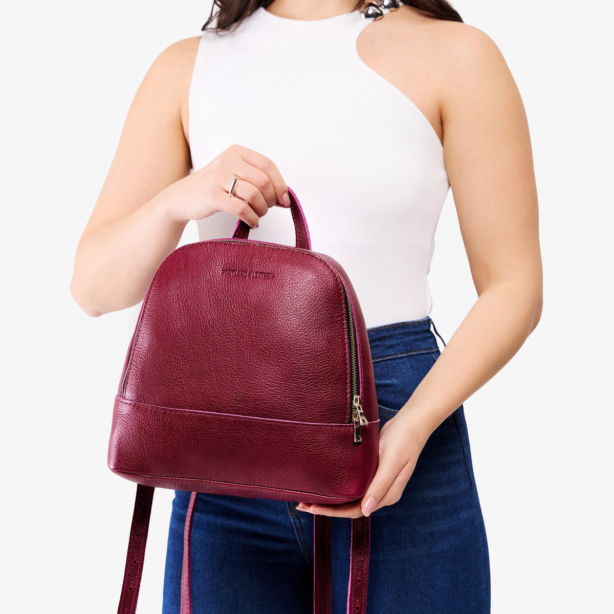 Orchid | Model holding leather backpack with debossed Portland Leather logo on front