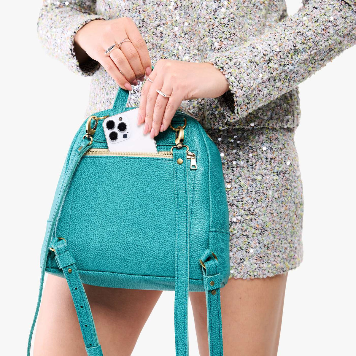 Seafoam | Model pulling smartphone out of back zipper pocket of a leather backpack