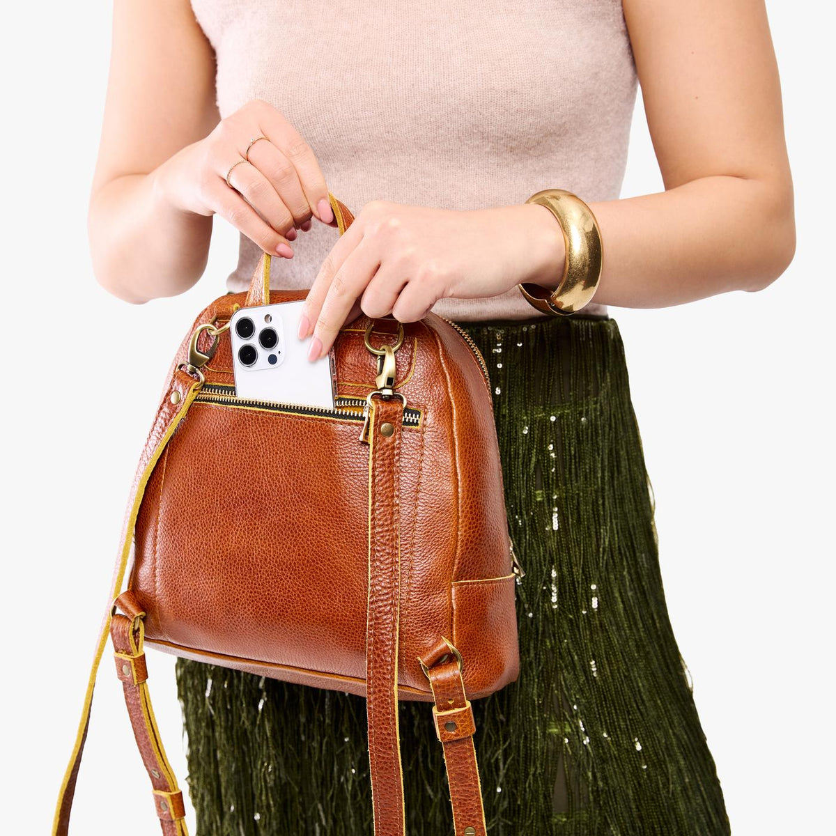 Sienna | Model pulling smartphone out of back zipper pocket of a leather backpack