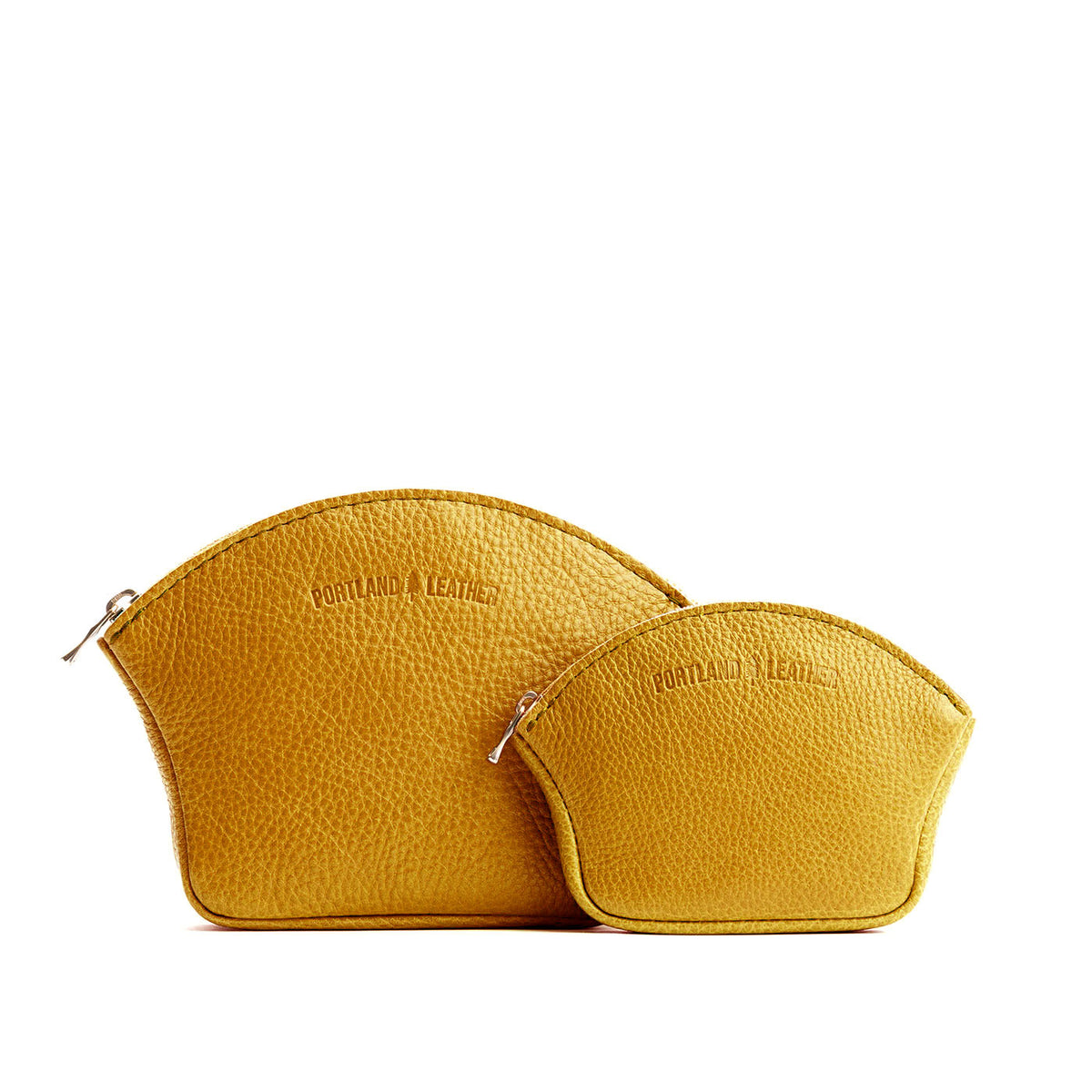 Sunshine | Comparison shot of small and large seashell shaped leather makeup bags with curved top zipper and flat bottom