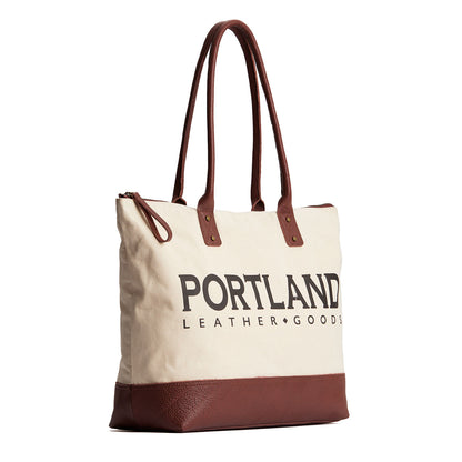 Canvas tote with zipper, leather bottom, and leather handles on a white background