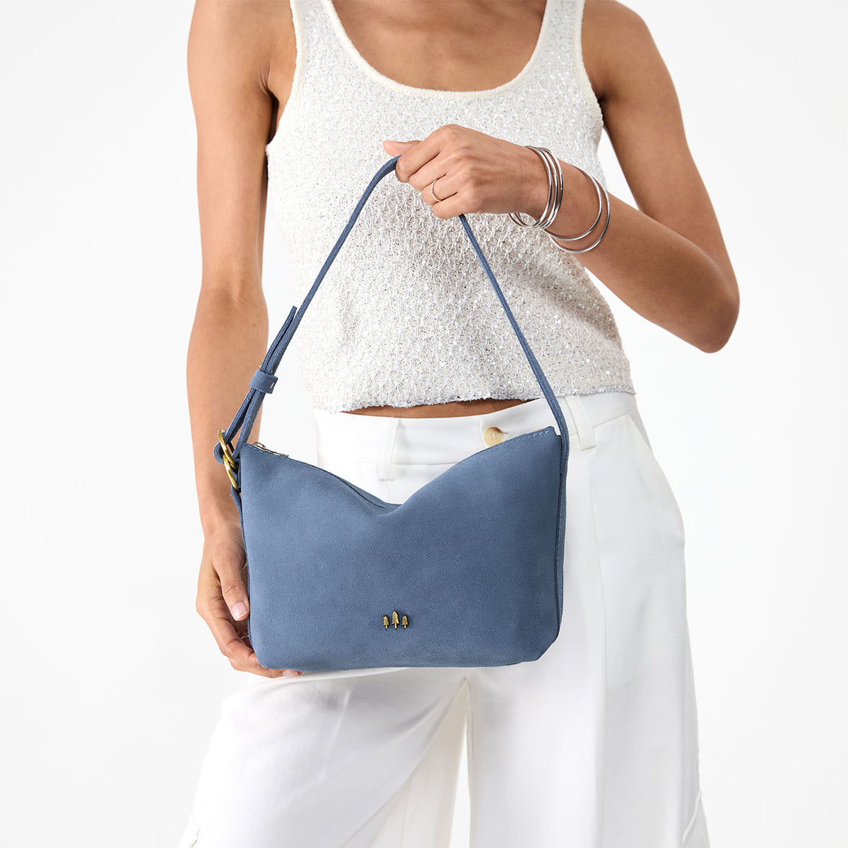 Denim*Small | Model holding a Slouchy Shoulder Bag that has a zipper opening and three metal tree emblems